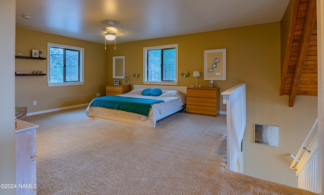 carpeted bedroom with ceiling fan and beam ceiling