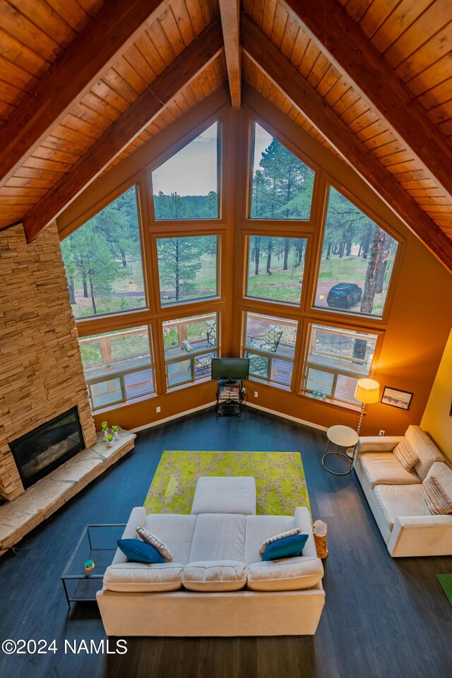 unfurnished living room with wood ceiling, dark hardwood / wood-style flooring, a stone fireplace, and vaulted ceiling with beams