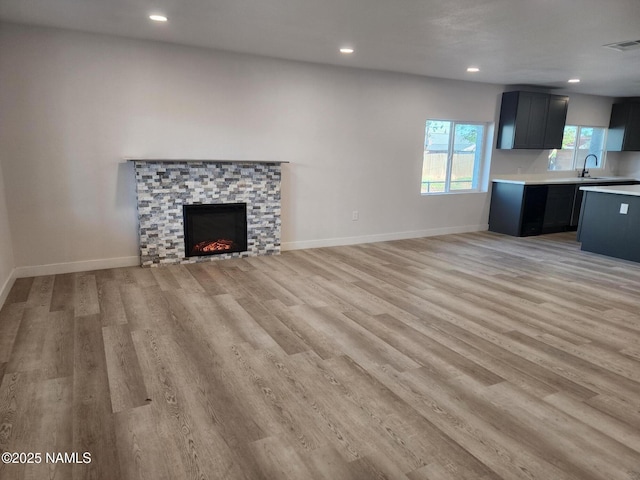 515 W Aspinwall St, Winslow, AZ 86047 - unfurnished living room featuring light wood finished floors, recessed lighting, a fireplace, baseboards, and a sink