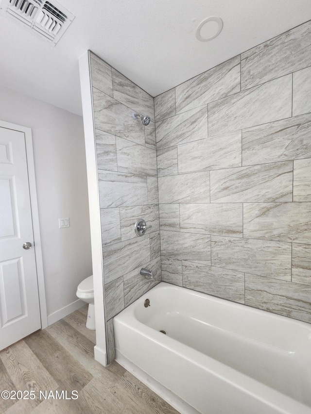 515 W Aspinwall St, Winslow, AZ 86047 - bathroom featuring toilet, wood finished floors, shower / bathtub combination, and baseboards