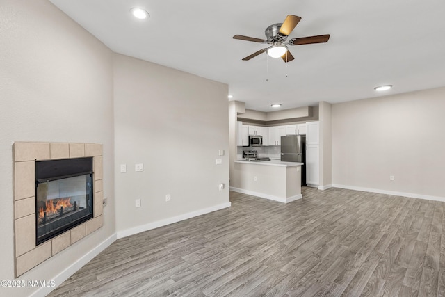 unfurnished living room with a fireplace, light hardwood / wood-style floors, and ceiling fan