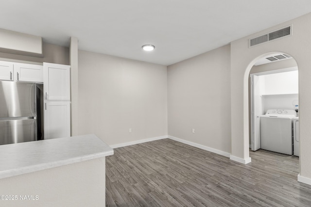 kitchen featuring washer and dryer, white cabinets, stainless steel fridge, and light hardwood / wood-style flooring