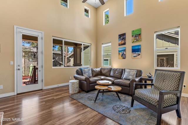 living room with wood finished floors, a wealth of natural light, baseboards, and ceiling fan
