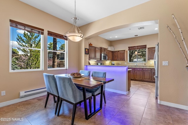 dining room with baseboard heating, arched walkways, visible vents, and baseboards