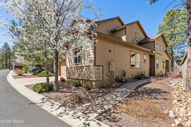 view of side of home featuring an attached garage, driveway, and board and batten siding