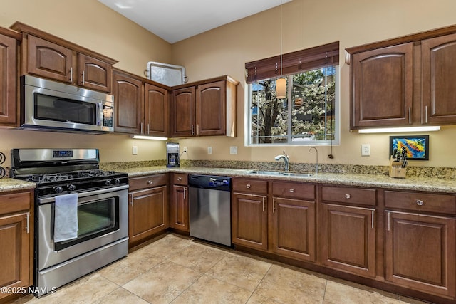 kitchen featuring light tile patterned floors, stainless steel appliances, a sink, and light stone counters