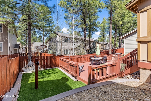 view of yard featuring a wooden deck, a residential view, outdoor dining area, and a fenced backyard