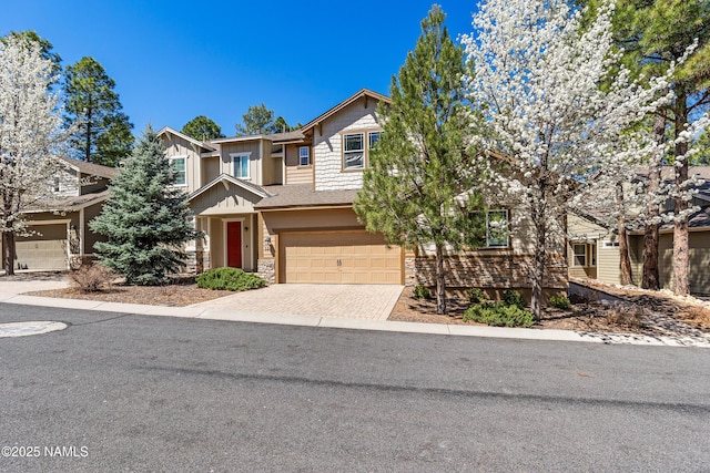 view of front of property with stone siding, an attached garage, and decorative driveway