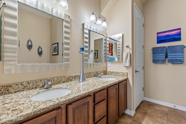 full bathroom with baseboards, a sink, and double vanity