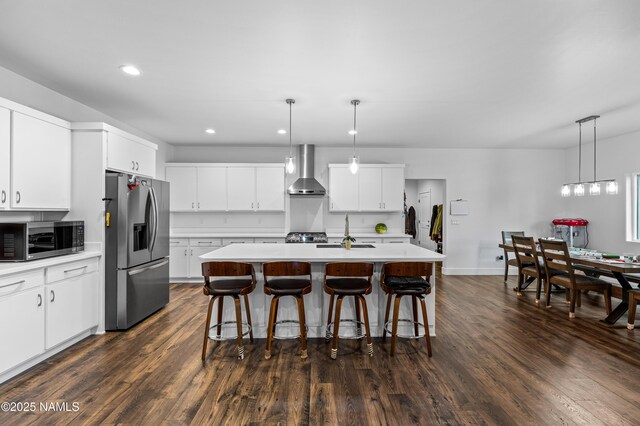8441 N Fleming Dr, Flagstaff, AZ 86004 - kitchen with stainless steel appliances, wall chimney range hood, a sink, light countertops, and a kitchen breakfast bar