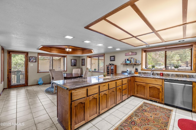 2201 N Rio De Flag Dr, Flagstaff, AZ 86004 - kitchen featuring stainless steel dishwasher, a peninsula, brown cabinetry, light tile patterned flooring, and plenty of natural light
