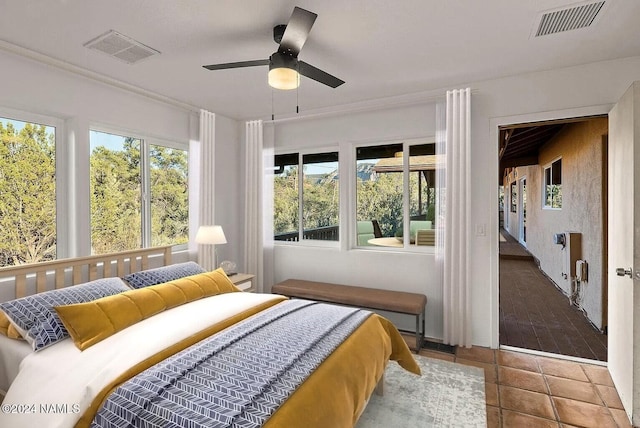 tiled bedroom featuring ceiling fan and multiple windows