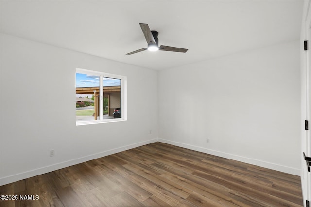 empty room with dark wood-type flooring, a ceiling fan, and baseboards