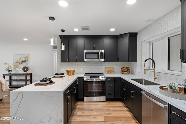 kitchen featuring stainless steel appliances, a sink, dark cabinets, a peninsula, and recessed lighting