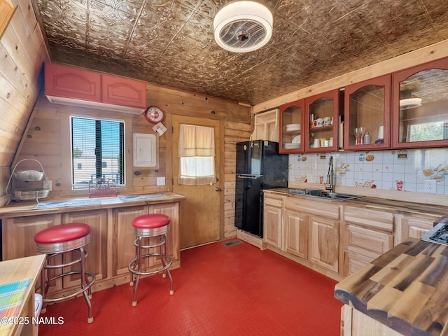 7284 N Buck Ridge Rd, Williams, AZ 86046 - kitchen featuring freestanding refrigerator, an ornate ceiling, wooden walls, glass insert cabinets, and a breakfast bar