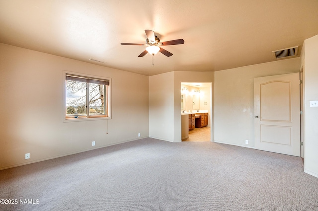 unfurnished bedroom with ensuite bath, visible vents, a ceiling fan, and light colored carpet