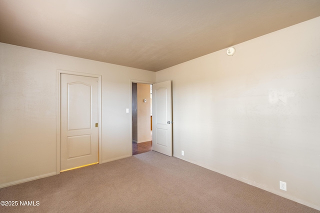 carpeted empty room featuring baseboards