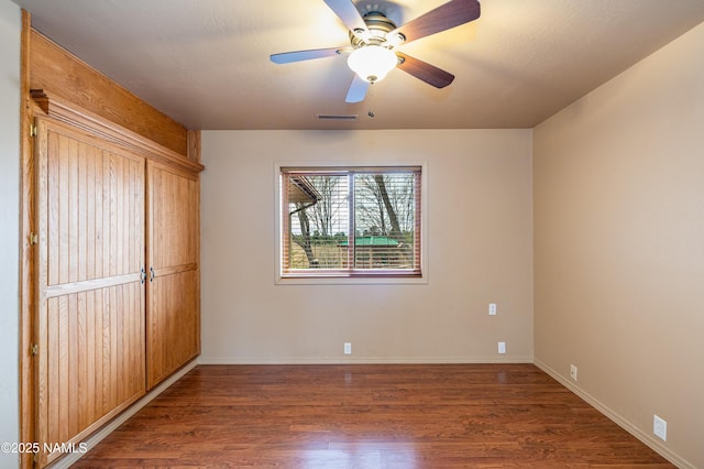 unfurnished room with baseboards, ceiling fan, visible vents, and wood finished floors