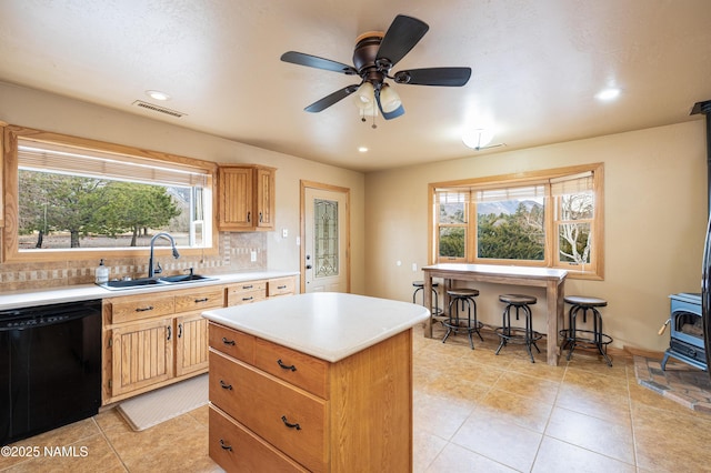 kitchen featuring black dishwasher, visible vents, decorative backsplash, a wood stove, and a sink