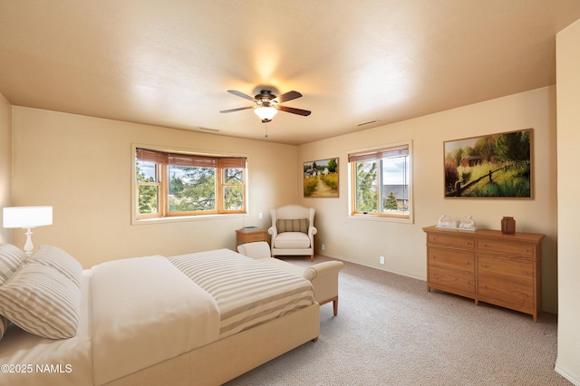 bedroom with light carpet, ceiling fan, visible vents, and baseboards