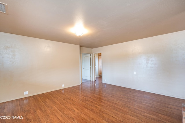 spare room with visible vents, baseboards, and wood finished floors