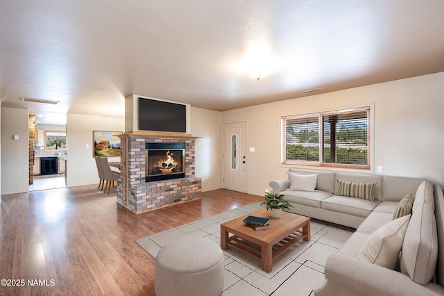 living area with a healthy amount of sunlight, light wood finished floors, a fireplace, and visible vents