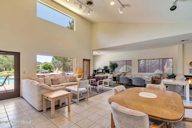 dining area with a towering ceiling, rail lighting, and light tile patterned floors