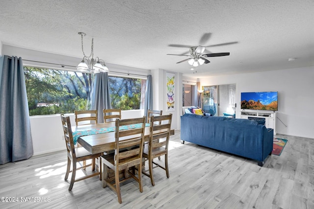 dining area with ceiling fan with notable chandelier, light hardwood / wood-style floors, and a textured ceiling