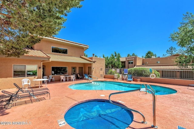 view of swimming pool with a hot tub and a patio