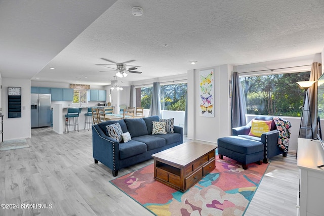 living room with light wood-type flooring, plenty of natural light, and a textured ceiling