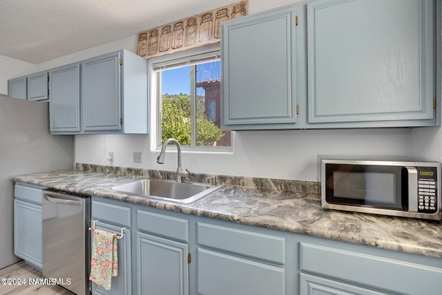 kitchen with sink, a textured ceiling, and appliances with stainless steel finishes