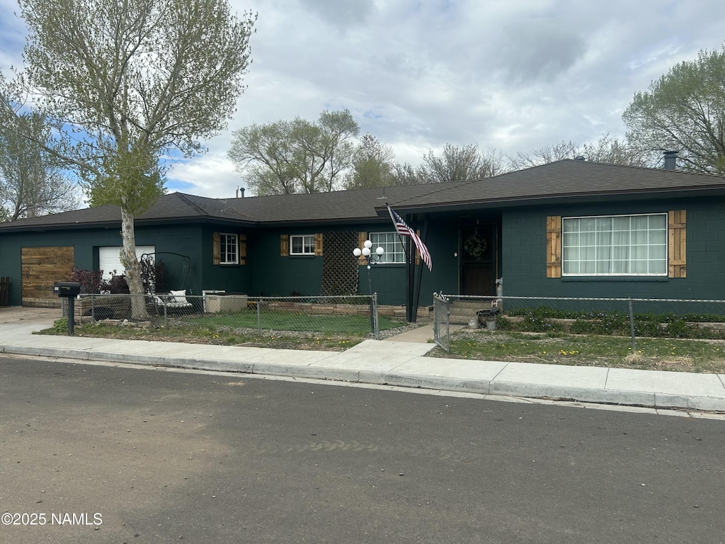 ranch-style house with a fenced front yard and an attached garage