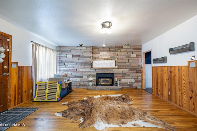 502 N Humbolt St, Williams, AZ 86046 - living room featuring wooden walls, a wainscoted wall, wood finished floors, and a stone fireplace