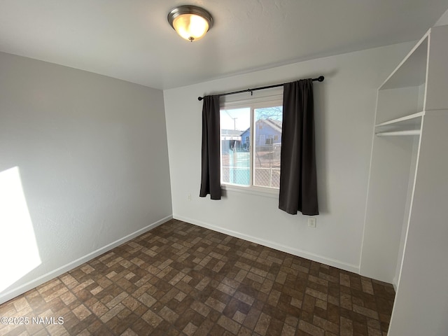 empty room featuring brick floor and baseboards