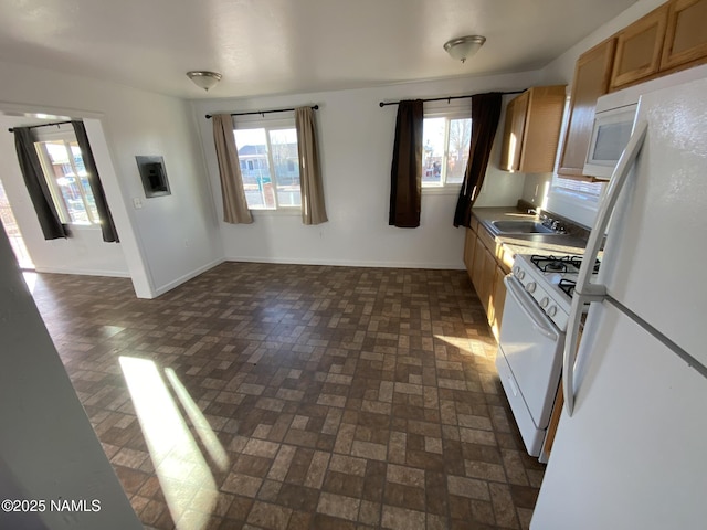 kitchen featuring white appliances, baseboards, brown cabinetry, brick floor, and a sink