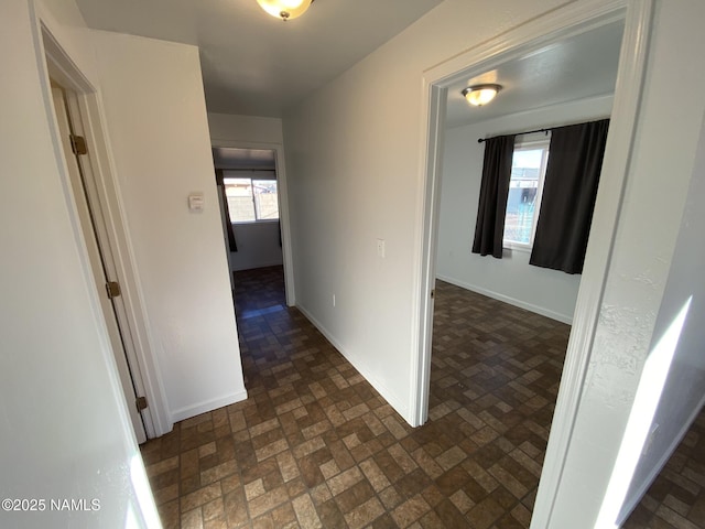 hall with brick floor, plenty of natural light, and baseboards