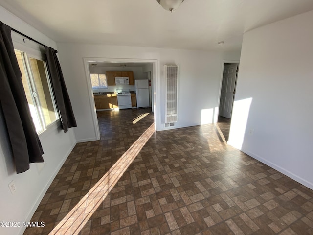 spare room featuring brick floor and baseboards