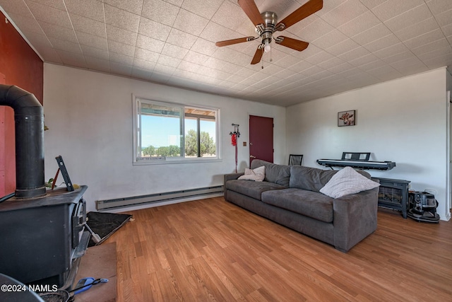 living room with a wood stove, ceiling fan, hardwood / wood-style floors, and a baseboard radiator