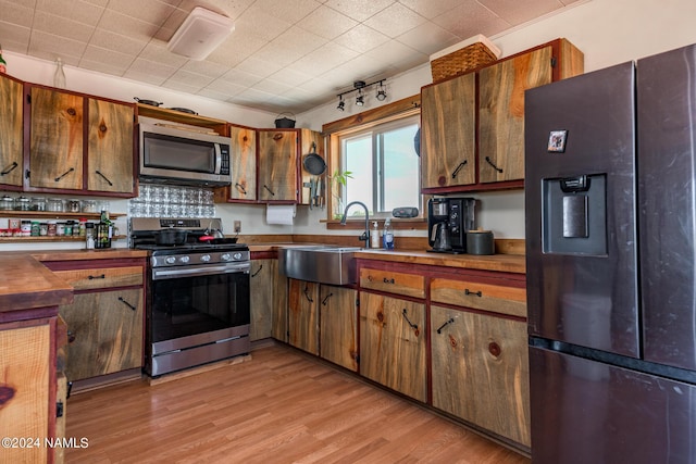 kitchen with light hardwood / wood-style floors, sink, decorative backsplash, and stainless steel appliances