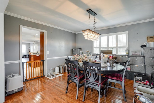 dining area with crown molding, hardwood / wood-style flooring, and a chandelier