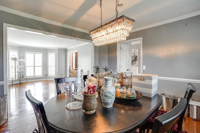 dining area featuring wood-type flooring, an inviting chandelier, and crown molding