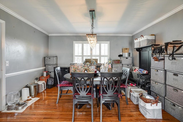 dining room with crown molding, hardwood / wood-style floors, and a chandelier