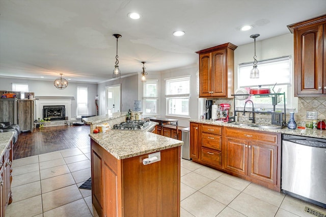 kitchen featuring hanging light fixtures, appliances with stainless steel finishes, light stone counters, light hardwood / wood-style floors, and a kitchen island