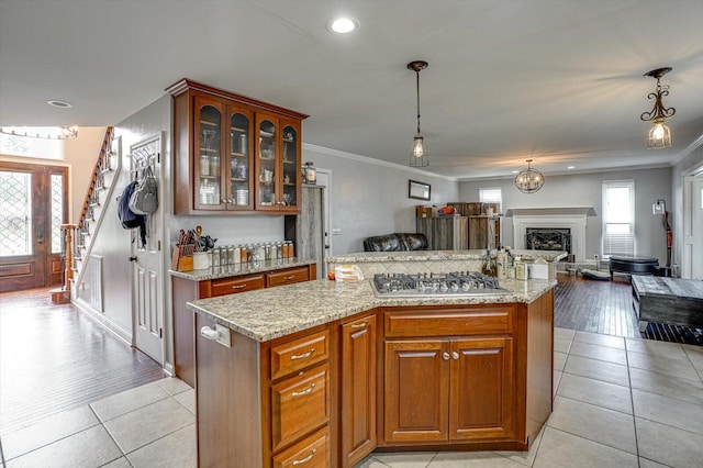 kitchen with pendant lighting, stainless steel gas stovetop, light stone counters, and light hardwood / wood-style floors