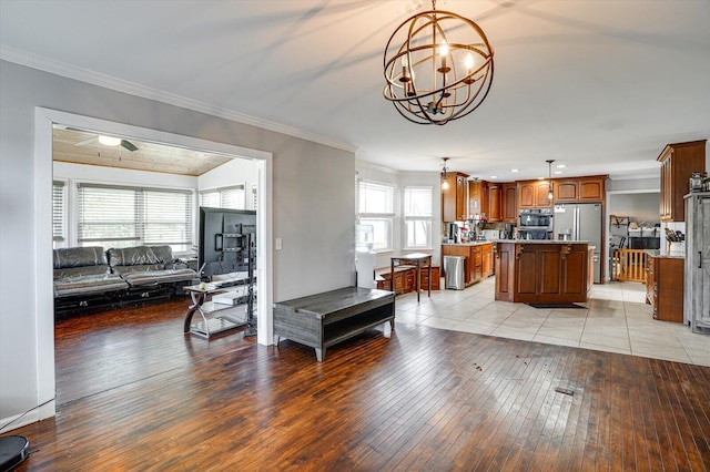 interior space featuring a center island, stainless steel appliances, ornamental molding, a chandelier, and light wood-type flooring