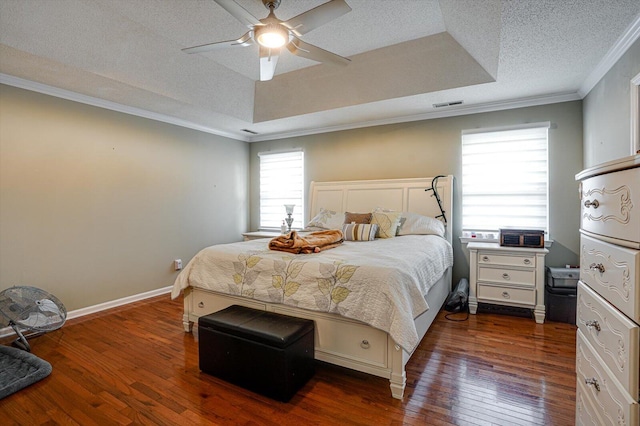 bedroom with crown molding, a tray ceiling, dark hardwood / wood-style floors, ceiling fan, and a textured ceiling