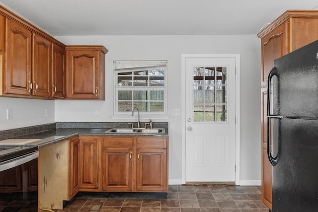 kitchen featuring black refrigerator, stainless steel stove, and sink