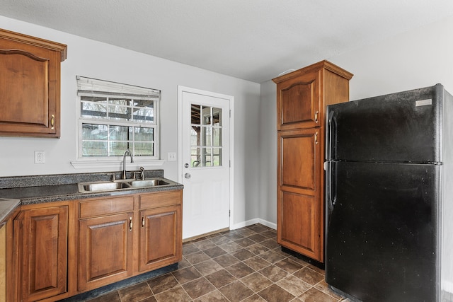 kitchen featuring a textured ceiling, black refrigerator, and sink