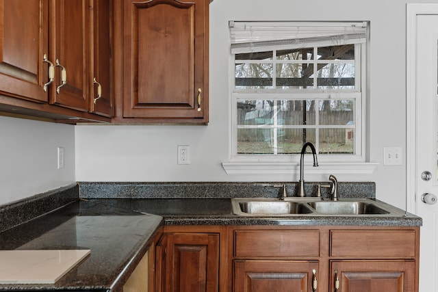 kitchen with a healthy amount of sunlight, sink, and dark stone counters