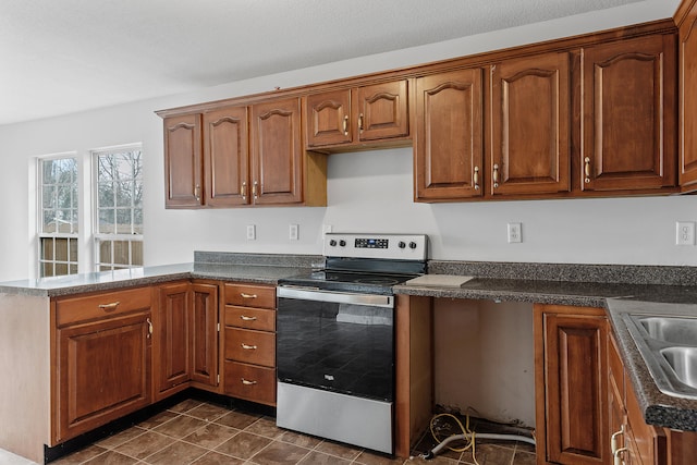 kitchen with dark tile patterned flooring, stainless steel electric range, kitchen peninsula, and sink